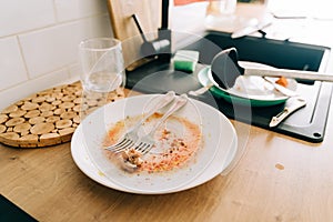 Wooden kitchen tabletop with black sink and dirty messy dish