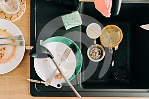 Wooden kitchen tabletop with black sink and dirty messy dish