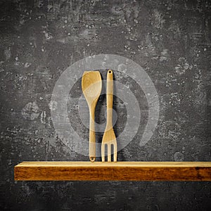 Wooden kitchen tools on wooden shelf. Copy space for your decoration and products. Dark gray retro wall background.