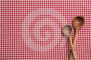 Wooden kitchen utensils on red checkered picnic tablecloth, top view, copy space