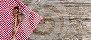 Wooden kitchen utensils on red tablecloth on wooden table, top view, copy space
