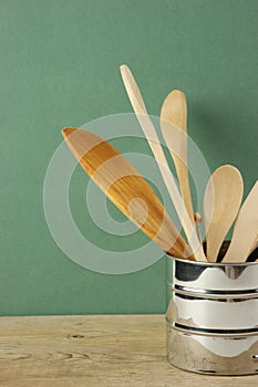 Wooden kitchenware in metal jug  on old wooden table