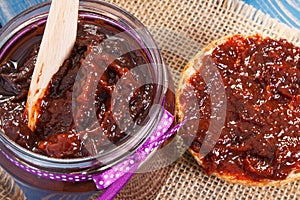 Wooden knife and plum marmalade or jam for preparing fresh sandwiches, healthy sweet breakfast concept