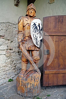 Wooden knight with sword and shield stands near entrance to castle