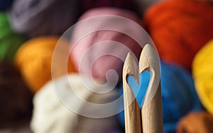 Wooden knitting needles on background of colorful merino wool ba