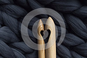 Wooden knitting needles on background of grey merino wool blanke