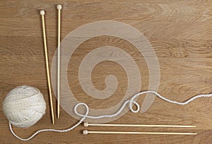 Wooden knitting needles and ball of yarn on wood background. Top view