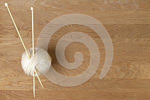 Wooden knitting needles and ball of yarn on wood background. Top view