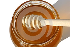 A wooden ladle lies in honey in a jar.
