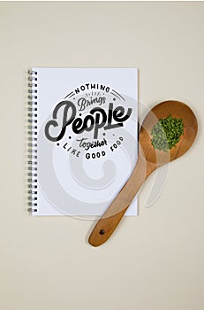 Wooden ladle with some herb spice and a blank notebook page