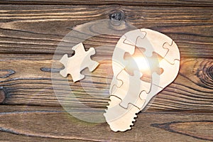 Wooden lamp from puzzles on a wooden background.