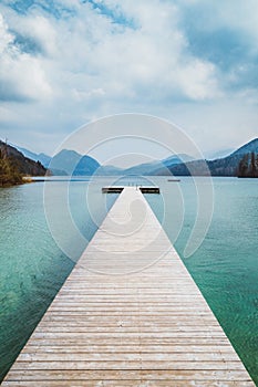 Wooden landing stage with alpine lake in summer