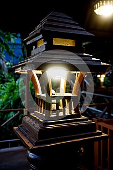 Wooden lantern with light bulb at baluster