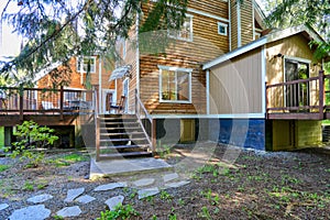 Wooden large American house with natural brown tone with white trim and green summer nature