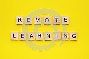 Wooden letter cubes on yellow background with phrase remote learning.