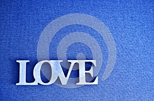 Wooden letters forming word LOVE written on grey canvas texture background made of Classic Blue 2020 color. Color of year 2020