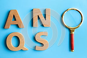 Wooden letters and magnifier glass on blue background, flat lay. Find keywords concept