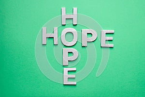 Wooden letters, making the word "hope", on the green wall, the concept of hope and belief