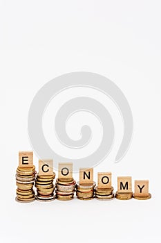 Wooden letters, put on stacks of coins of decreasing height, and composing the word `economy` on a white background