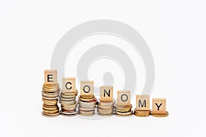 Wooden letters, put on stacks of coins of decreasing height, and composing the word `economy` on a white background