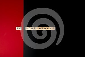 Wooden letters on a red and black background forming the word â€œreconfinementâ€. Second wave during Coronavirus pandemic concept