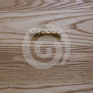 Wooden letters spelling August on a wooden background