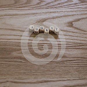 Wooden letters spelling August on a wooden background