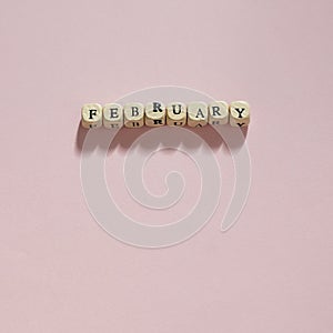 Wooden letters spelling February on a pale pink background