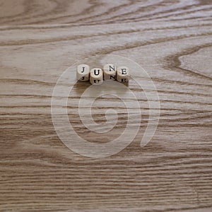 Wooden letters spelling June on a wooden background