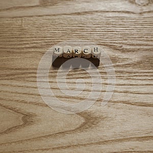 Wooden letters spelling March on a wooden background