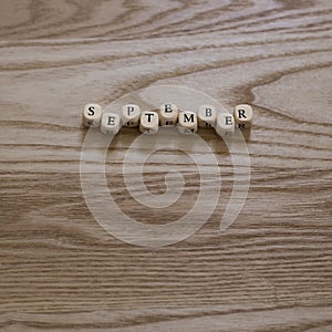 Wooden letters spelling September on a wooden background