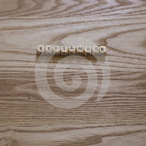 Wooden letters spelling September on a wooden background