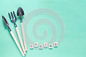 Wooden letters spring on a green background. Gardening at home. top view. wood letters. flatiay. Tools for gardening at