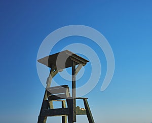 Wooden lifeguard chair on a blue sky beach