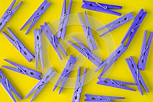 Wooden lilac-purple clothespins scattered on a yellow background. View from above. Copy space. Flat lay. The concept is natural,