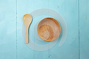 wooden little spoon and bowl on blue painted boards background
