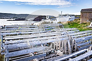 Wooden lobster traps overlooking fishing boats dragged-up on shore along the Canadian East coast.