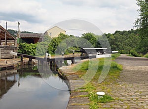 Wooden lock gates on the calder hand hebble navigation canal in front of the basin in sowerby bridge west yorkshire surrounded by