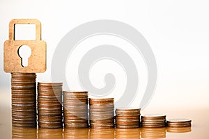 Wooden lock and stack of coins in concept of savings.