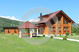 Wooden log cabin house with stone gazebo and wooden tool shed