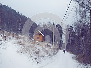 Wooden log house in winter forest and woman silhouette