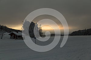 Wooden lonely house in snow valley on sunset background in Levi, Finland