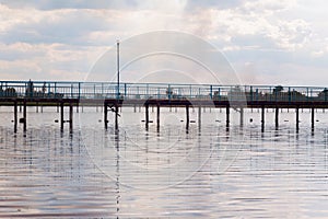 Wooden long bridge over a sea plait, river at sunset in perpektive, against a background of reeds, landscape