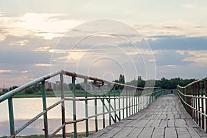 Wooden long bridge over a sea plait, river at sunset in perpektive, against a background of reeds, landscape