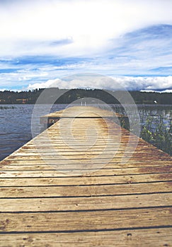 Wooden long empty pier on the lake shore in with vintage effect