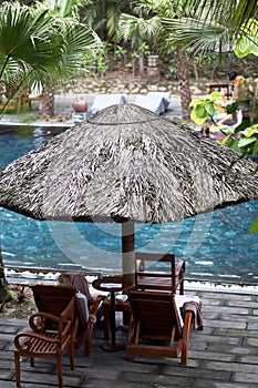 Wooden lounge chairs under a straw umbrella