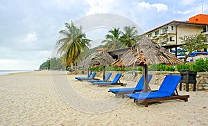 Wooden lounge / deck chairs and umbrella on paradise beach looking out to ocean