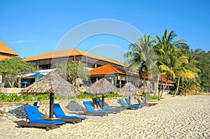 Wooden lounge / deck chairs and umbrella on paradise beach looking out to ocean