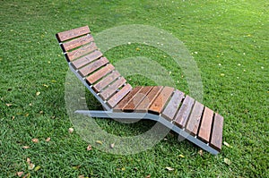 Wooden lounger on a green lawn in the park