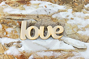 Wooden love sign on stone texture with snow